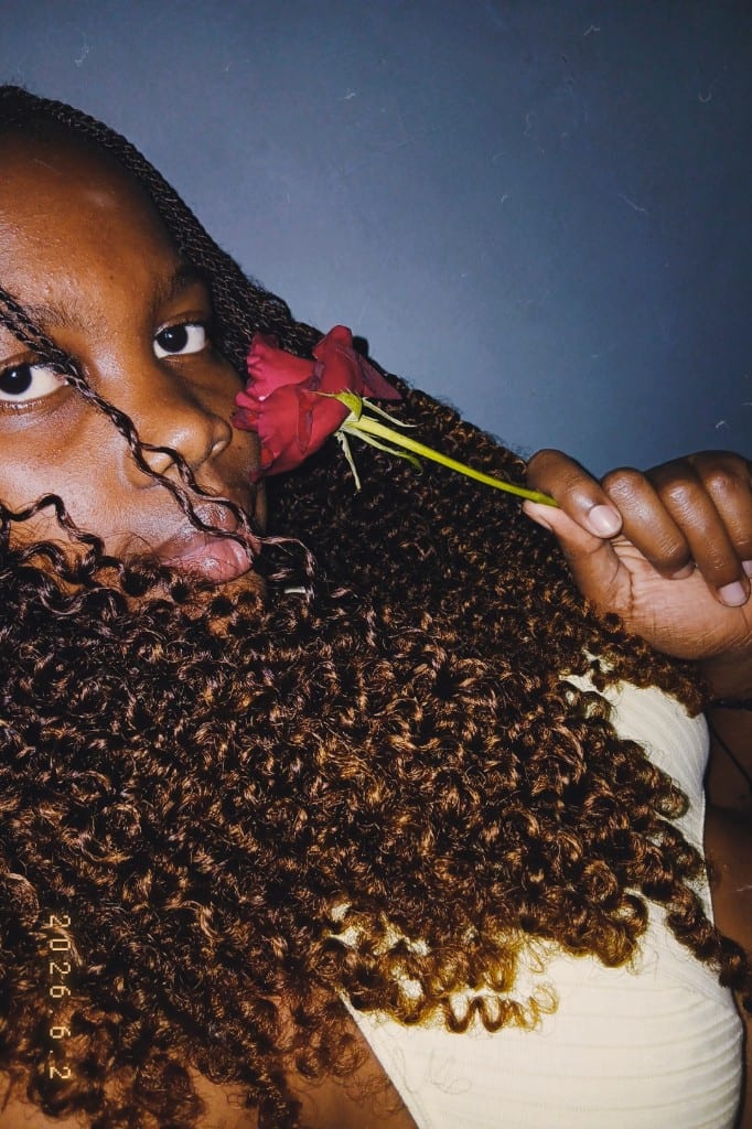 Percia deitada, com uma rosa vermelha junto ao rosto