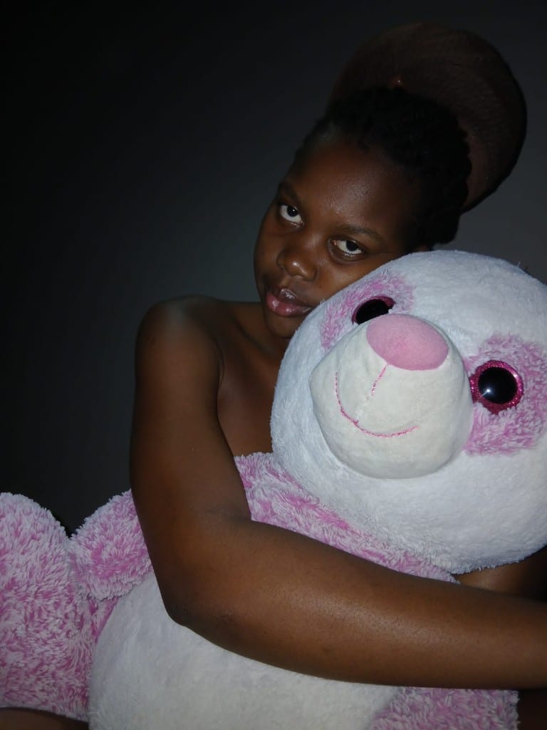 Percia abraçada a um urso de peluche cor-de-rosa